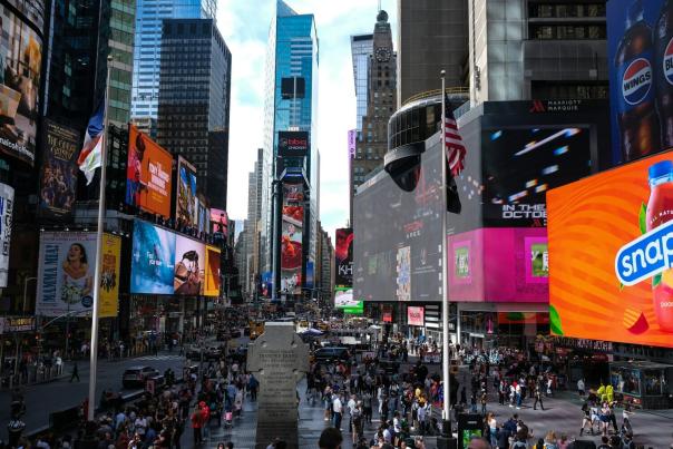 Crowded Times Square in New York City with bright billboards and skyscrapers surrounded by tourists during the day