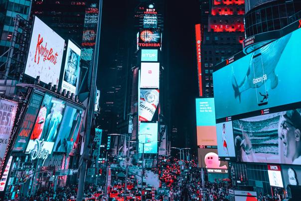 Times Square in New York City lit up at night with glowing billboards and busy street activity