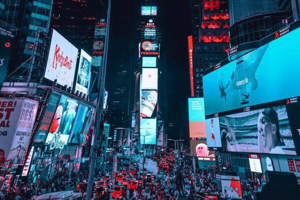 Times Square illuminated at night with crowds, bright billboards, and yellow cab traffic on the street below