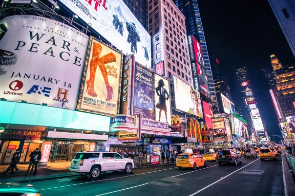 Times Square in New York City at night with neon lights, Broadway signs, and traffic on the busy Midtown Manhattan street