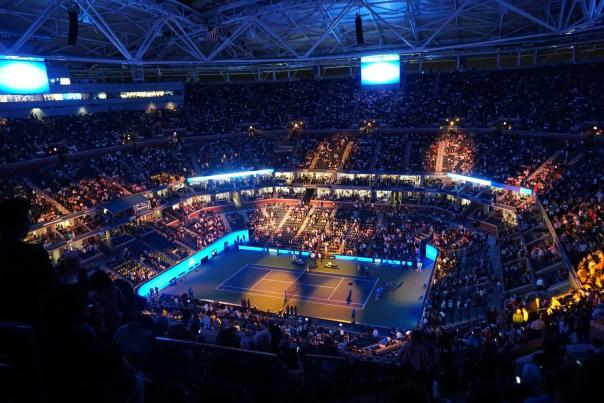 Packed tennis stadium crowd at a US Open match with dramatic arena energy