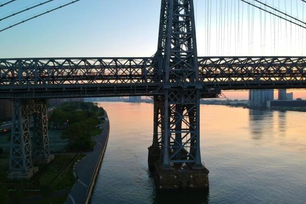 Aerial view of the Williamsburg Bridge spanning the East River at sunrise, connecting the Lower East Side and Brooklyn
