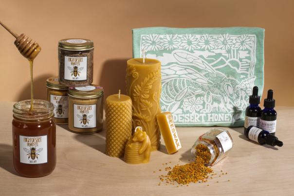 High Desert Honey Co. products including raw honey, wellness tinctures, beeswax candles, and a bee-themed t-shirt on display.