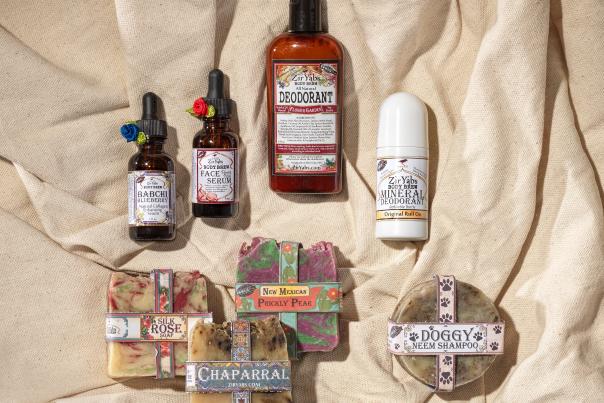 A collection of skincare products on beige fabric includes serums, deodorants, and soaps with colorful labels.