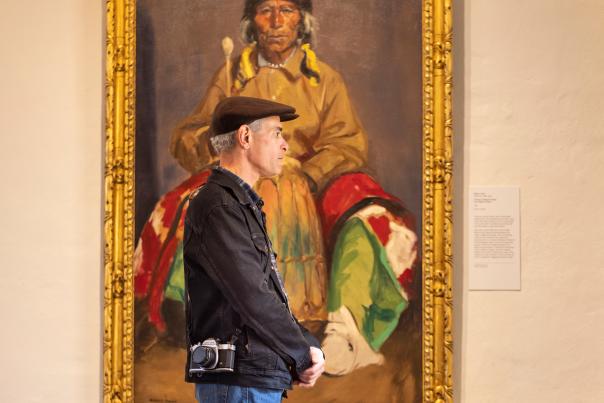 The author assumes his old museum guard stance at the New Mexico Museum of Art, in Santa Fe. Behind him is Robert Henri’s 1916 Portrait of Dieguito Roybal, San Ildefonso Pueblo.