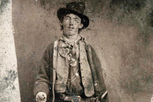 Bill the Kid poses for a ferro-type photo outside a Fort Sumner saloon in 1879 with a Winchester carbine and Colt revolver.