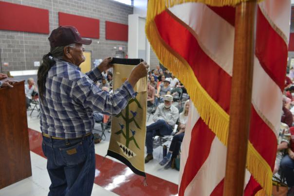 Auction volunteer Charlie Teller holds up a Tree of Life rug by Louise Harvey of Piñon, Arizona.