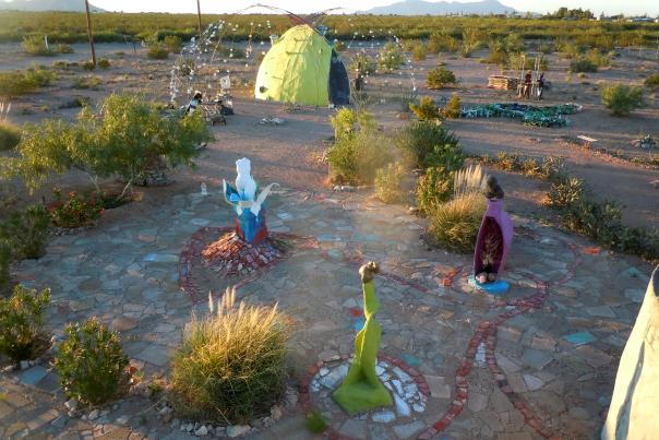 A whimsical desert garden features a mosaic pathway and brightly-painted sculptures.