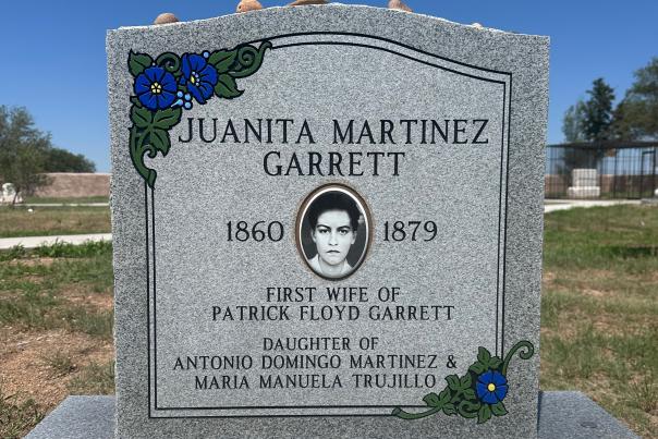 A gray headstone with flowers and a portrait of Juanita Martinez Garrett, who lived from 1860 to 1879.