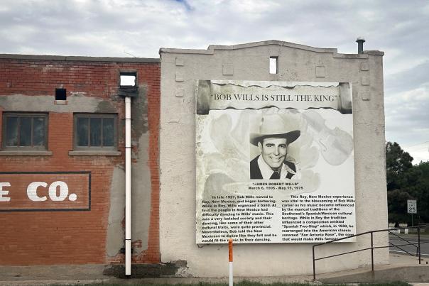 Outdoor mural featuring a portrait and biography of Bob Wills on the side of a building.