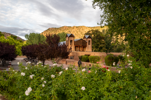 A tranquil courtyard garden with blooming roses welcomes visitors to El Santuario de Chimayó.