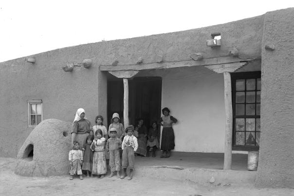 In Agua Fría, a family stands before an adobe home, circa 1912.