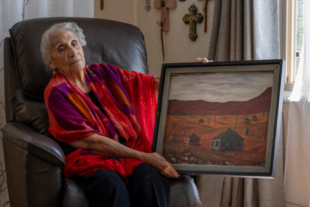 At her Albuquerque home, Petra Tovar Sánchez, born in Dawson in 1928, holds a painting of her former neighborhood.