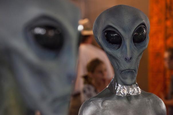 Close-up of two gray alien figures with large black eyes in a display setting.