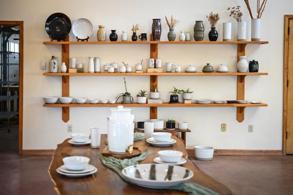 Sage Valley Pottery showroom with shelves of handmade ceramics and a table set with pottery dishes.