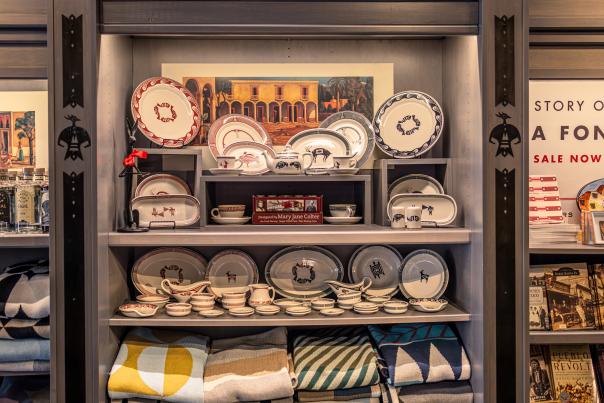 A display shelf with pottery, blankets, and books on southwestern themes.