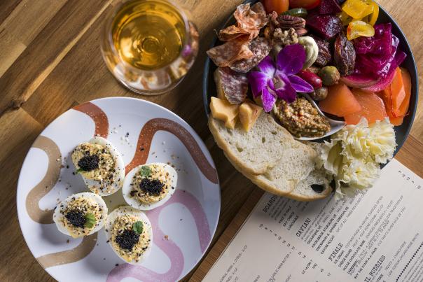 Deviled eggs topped with black caviar and herbs on a small serving plate.