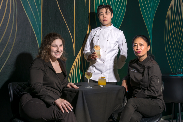 A portrait of three Alkemē co-owners standing together inside their richly decorated restaurant.