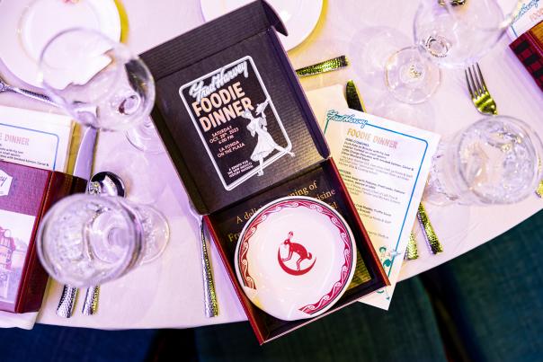 An overhead photo of a formal dinner place setting with a "Fred Harvey Foodie Dinner" box and menu.