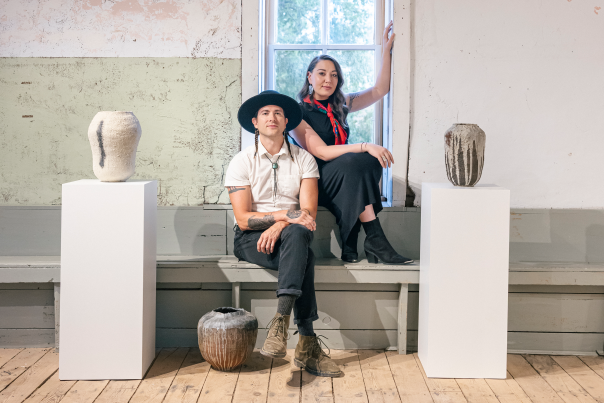 Two artists seated among ceramic sculptures inside Duende Gallery.