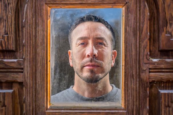 Vicente Telles stares into the mirrored door of his art studio in Albuquerque.