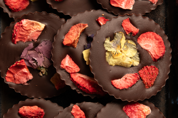 Ek.Chuah chocolate discs are decorated with strawberries and violet petals.