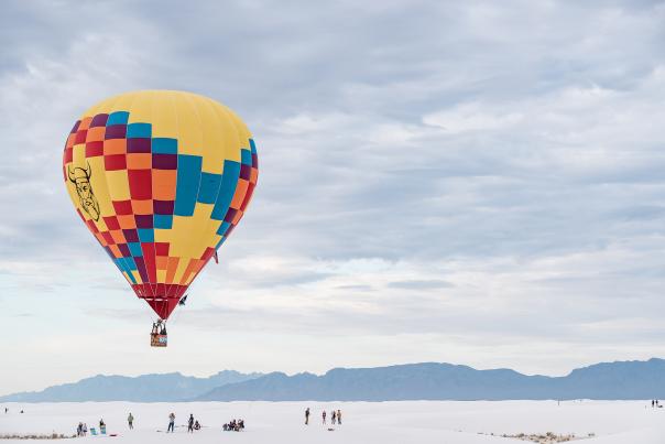 A colorful balloon floats over White Sands National Park at the Balloon & Music Festival.
