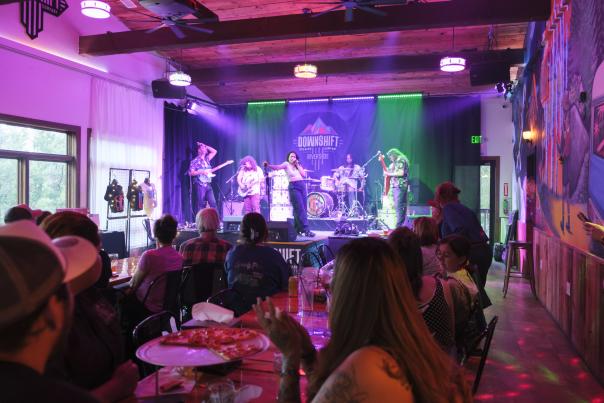 Red Light Cameras perform onstage at Ruidoso's Downshift Brewing Company, with lead singer Amanda Machon and the band lit by stage lights.