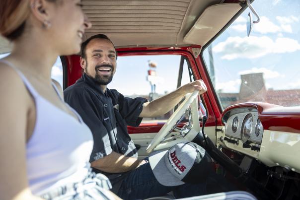 Chase waters smiling in the driver's seat of a red classic truck.