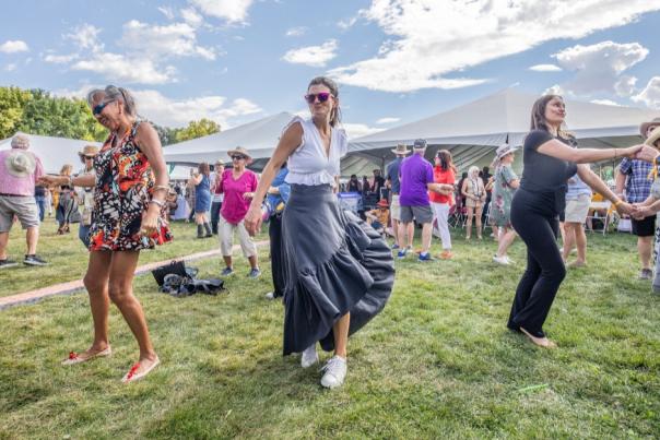 People dance joyfully on grass at an outdoor festival.