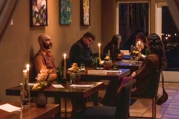 A softly lit dining room with stucco walls, modern chairs, and a fireplace creating a cozy atmosphere.