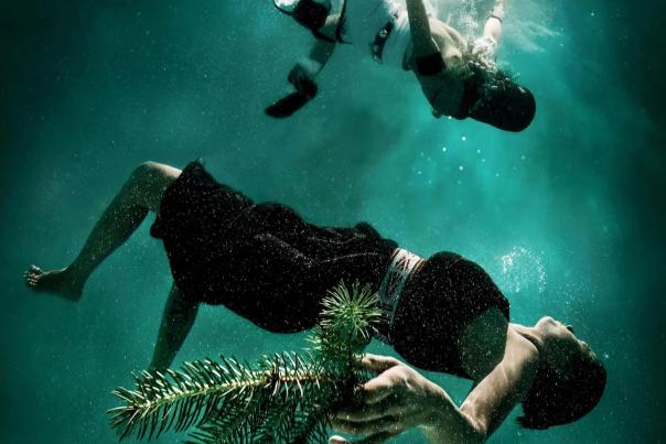Underwater photograph by Cara Romero showing two figures reaching toward each other.