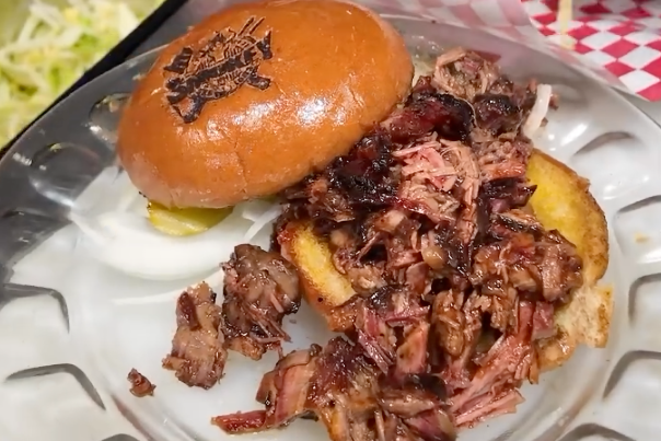 Pulled pork sandwich on a toasted bun, served with golden barbecue crust and sauce.