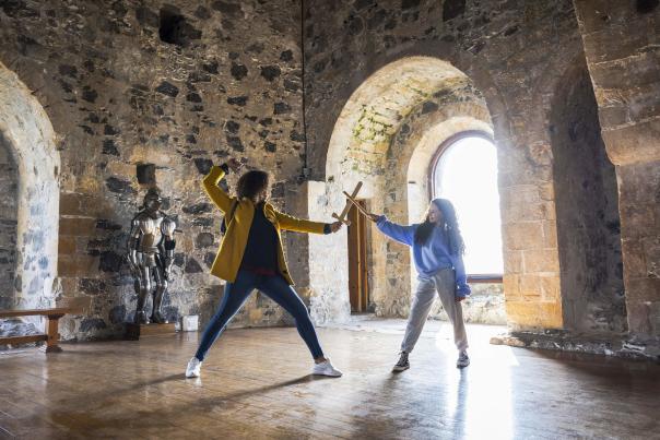 A mother and daughter play sword fights in Carrickfergus Castle