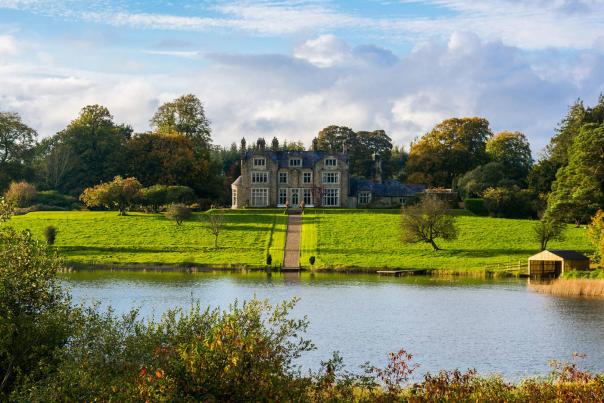 View of Blessingbourne Estate from afar with a lake and lush green gardens visible in front of the house