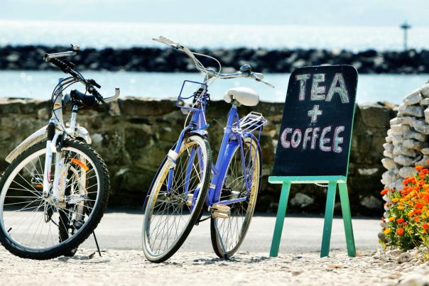 2 bikes propped up sitting beside a Tea and Coffee sign