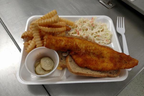 fried fish sandwich with side of French fries, Cole slaw, and pickles