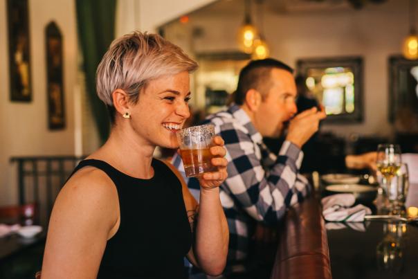 woman smiling at bar with bourbon