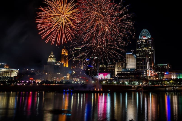 Several orange bursts of fireworks over Cincinnati seen from the Northern Kentucky riverbank on the Ohio