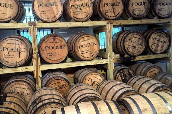Racks of bourbon barrels in a rickhouse, marked with the name of Old Pogue Distillery