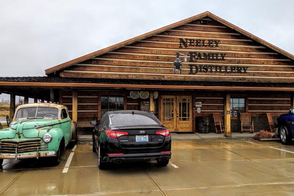 The exterior of Neeley Family Distillery, a wood building on the B-Line Bourbon trail in NKY, with an old bootlegger's car parked out front.