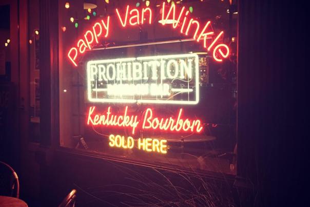 Pink Neon lettering spelling out Pappy Van Winkle Kentucky Bourbon" and a white sign that says Prohibition