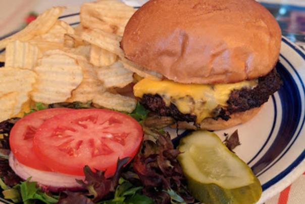 photo of a cheeseburger, garden on the side, with a side of potato chips