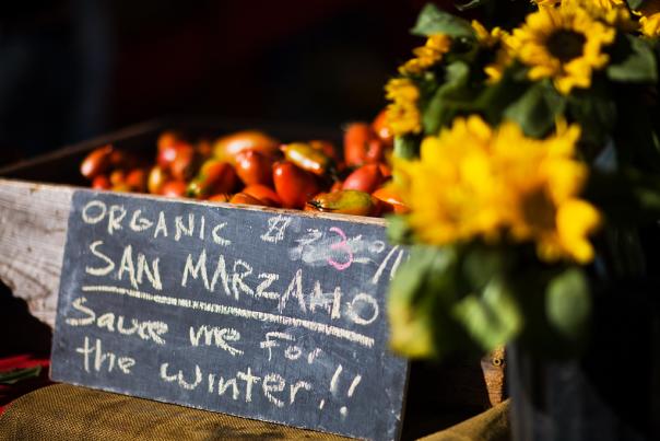 Farmer's Market sign next to sunflowers with San Marzano tomatoes in the background