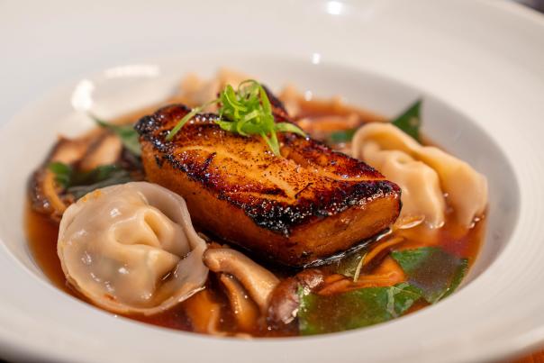 Seared salmon with dumplings and vegetables in a savory broth.