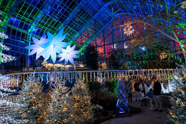 A model train passes above visitors on a lighted tracks amid light displays at Lauritzen Gardens.