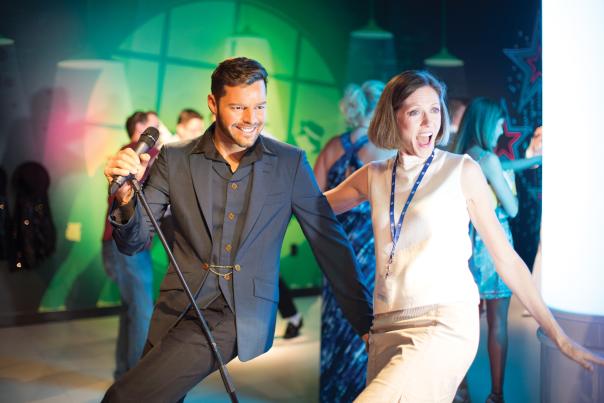 A woman posing with a wax figure of Ricky Martin singing at the Madame Tussauds attraction