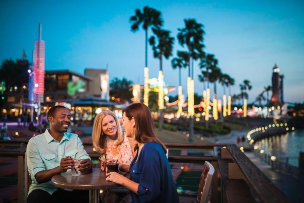 Three people sitting at a table, having drinks at Universal CityWalk at night