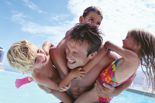 A father playing with his kids by a swimming pool