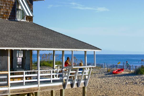 Visitors enjoy the fresh air and view from the wrap-around porch of their Outer Banks vacation rental.